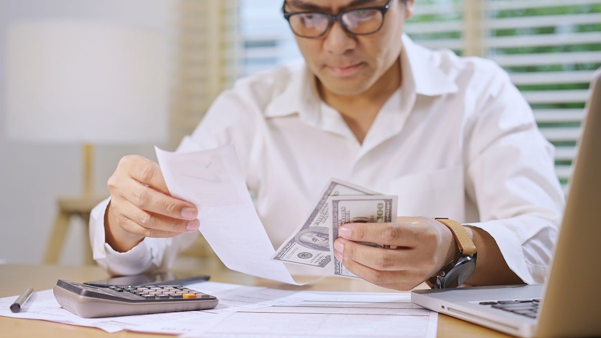 Man Managing Finances with Cash and Receipts NAV