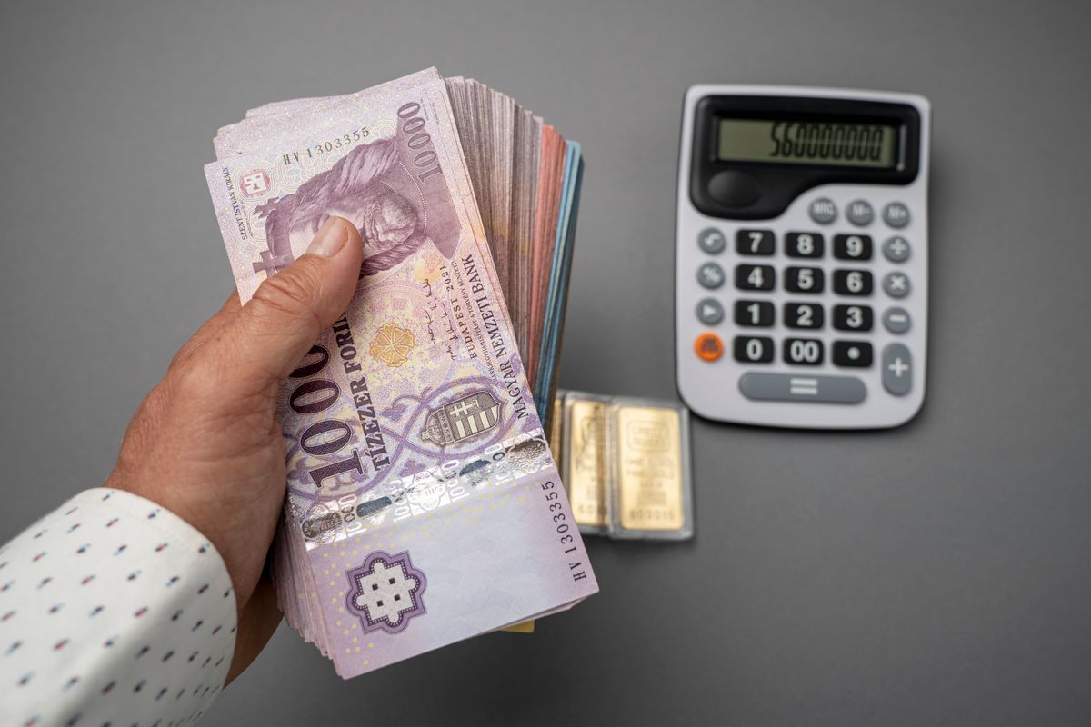 Hungarian forint money, Real estate investor man clutching a handful of banknotes. Large denominations, gold block, calculator. Inflation and financial situation in Hungary A NAV szigorít, ez azokat érinti akiknek van mulasztása