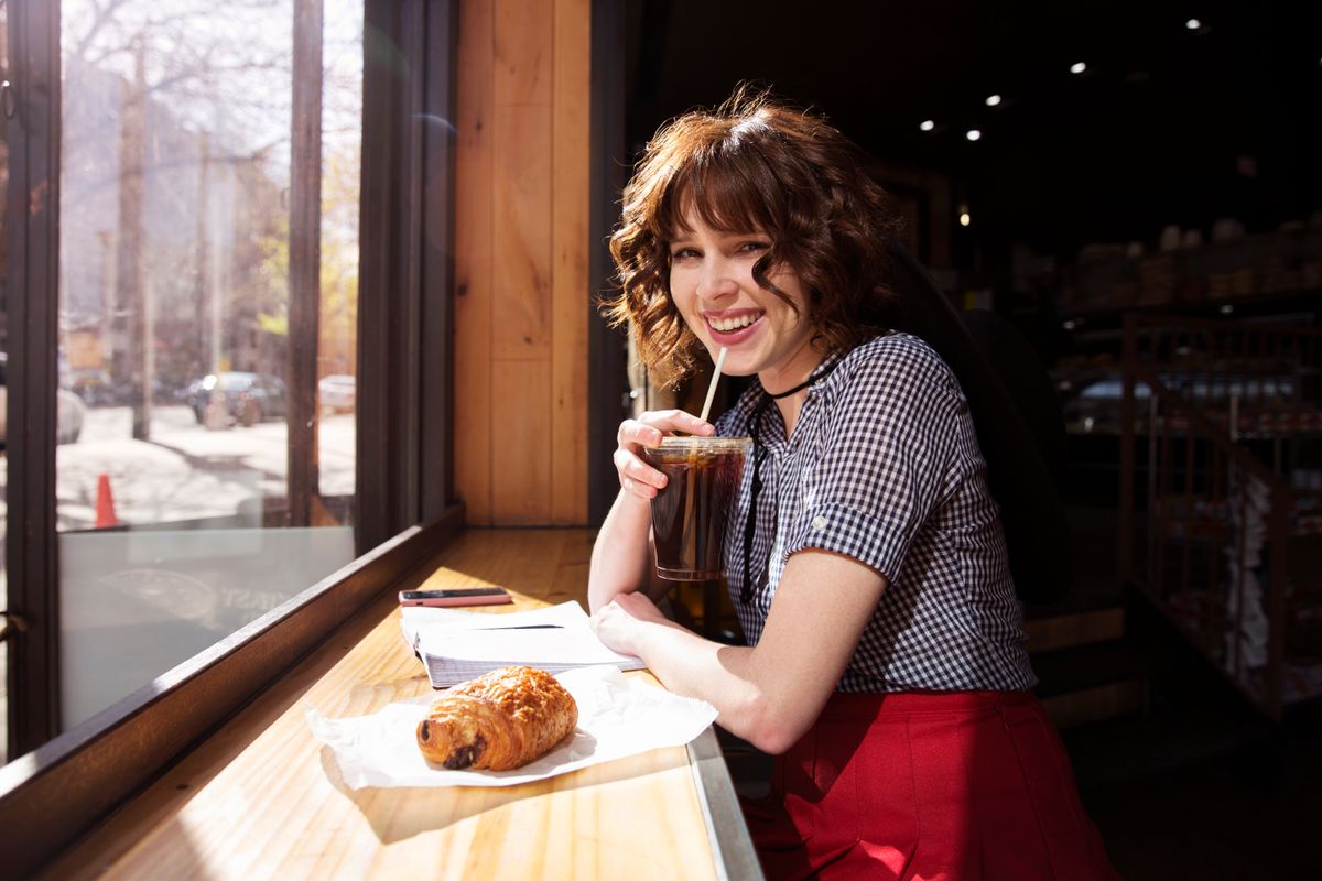 Portrait of happy woman drinking cola at cafe kóla