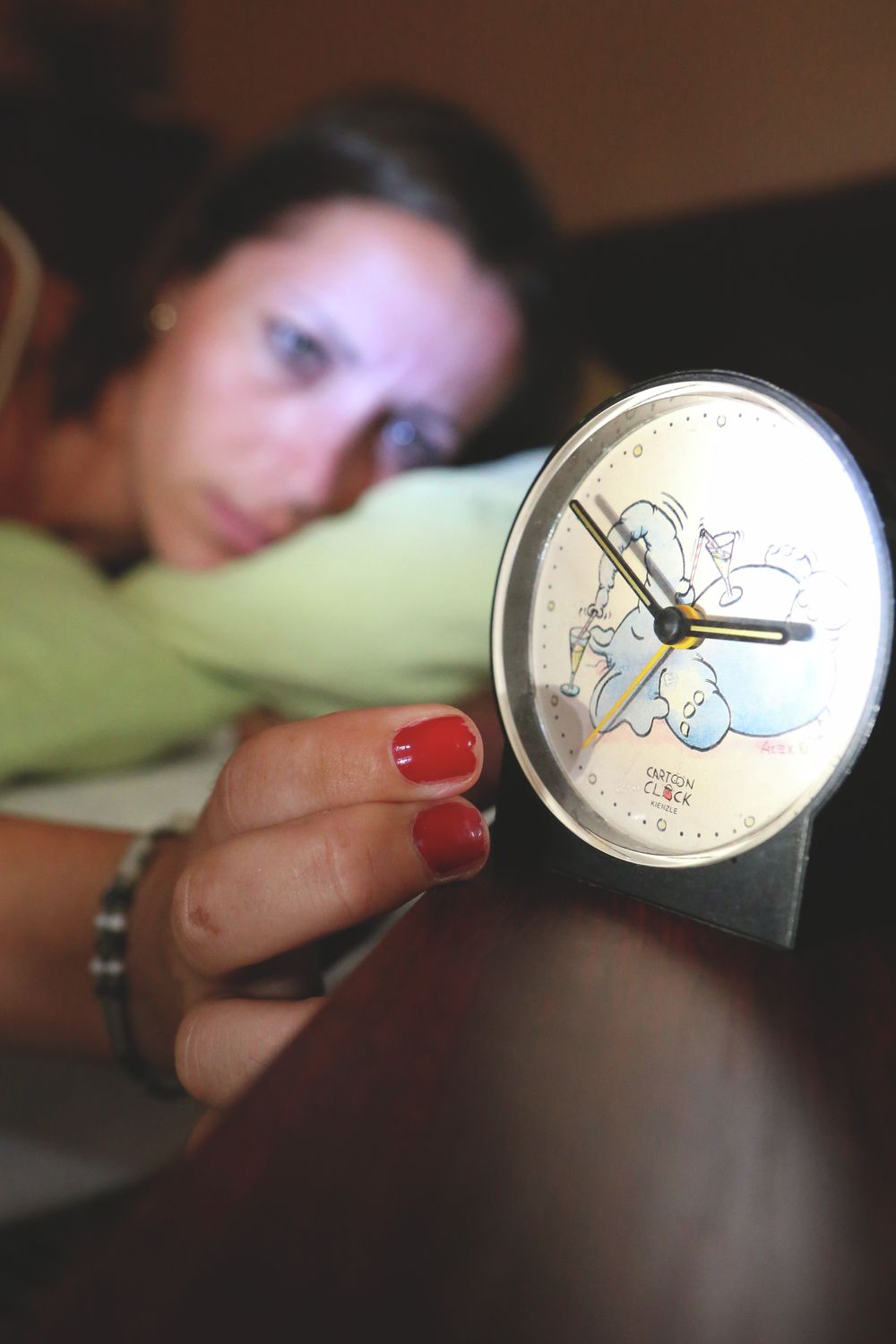 Alvás közben felébredt ember, nézi az órát. 